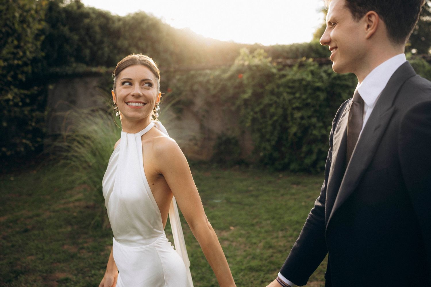 A romantic black and white wedding photograph showing a tender embrace in a natural outdoor setting.