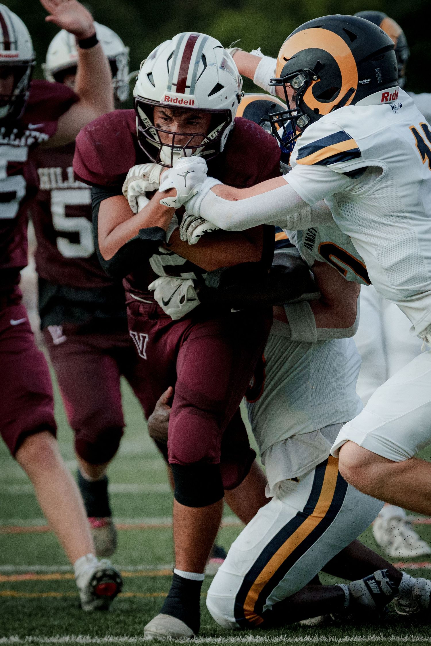 Verona football player in maroon jersey being tackled by opposing Rams defenders.