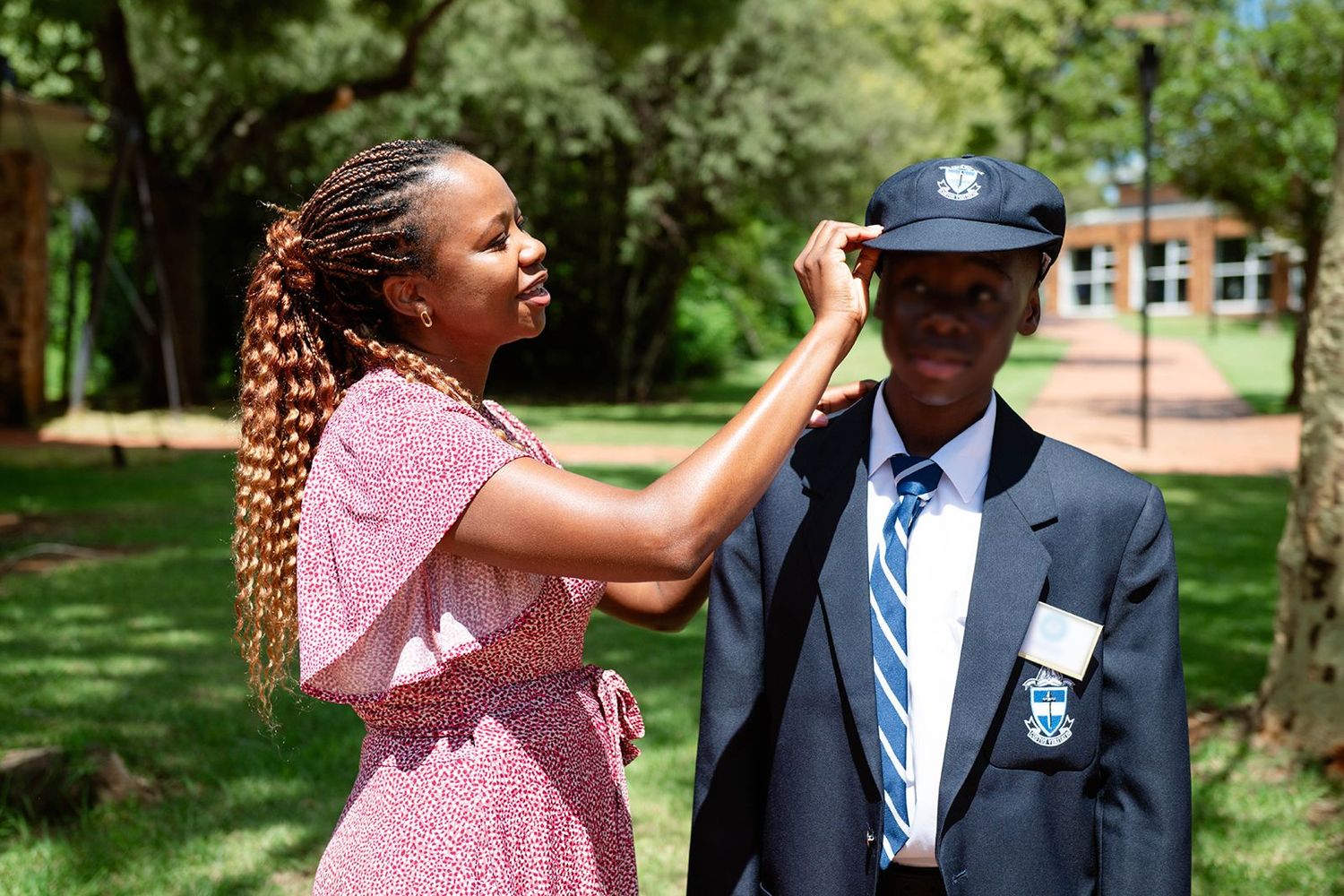 An image of a mother fixing his son's school uniform hat.