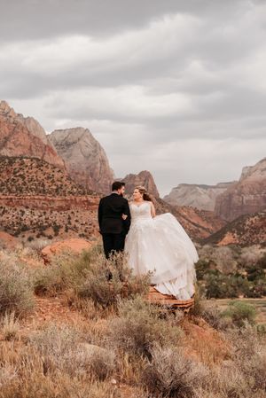 Bride and groom share a romantic moment at Zion National Park, surrounded by red rock canyon views.
