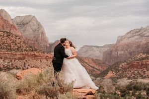 Bride and groom share a romantic kiss at Zion National Park with stunning red rock canyon views.
