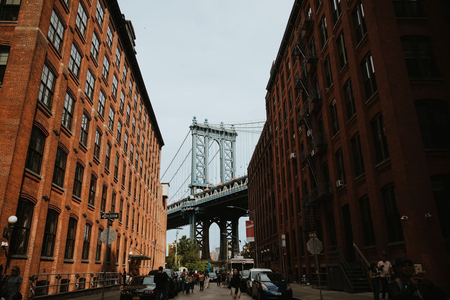 Street view of Manhattan Bridge framed by red brick buildings in DUMBO, Brooklyn, New York City.