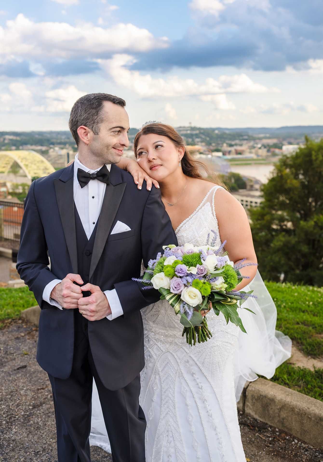 Bride and groom pose outdoors in wedding attire, at the view wedding venue