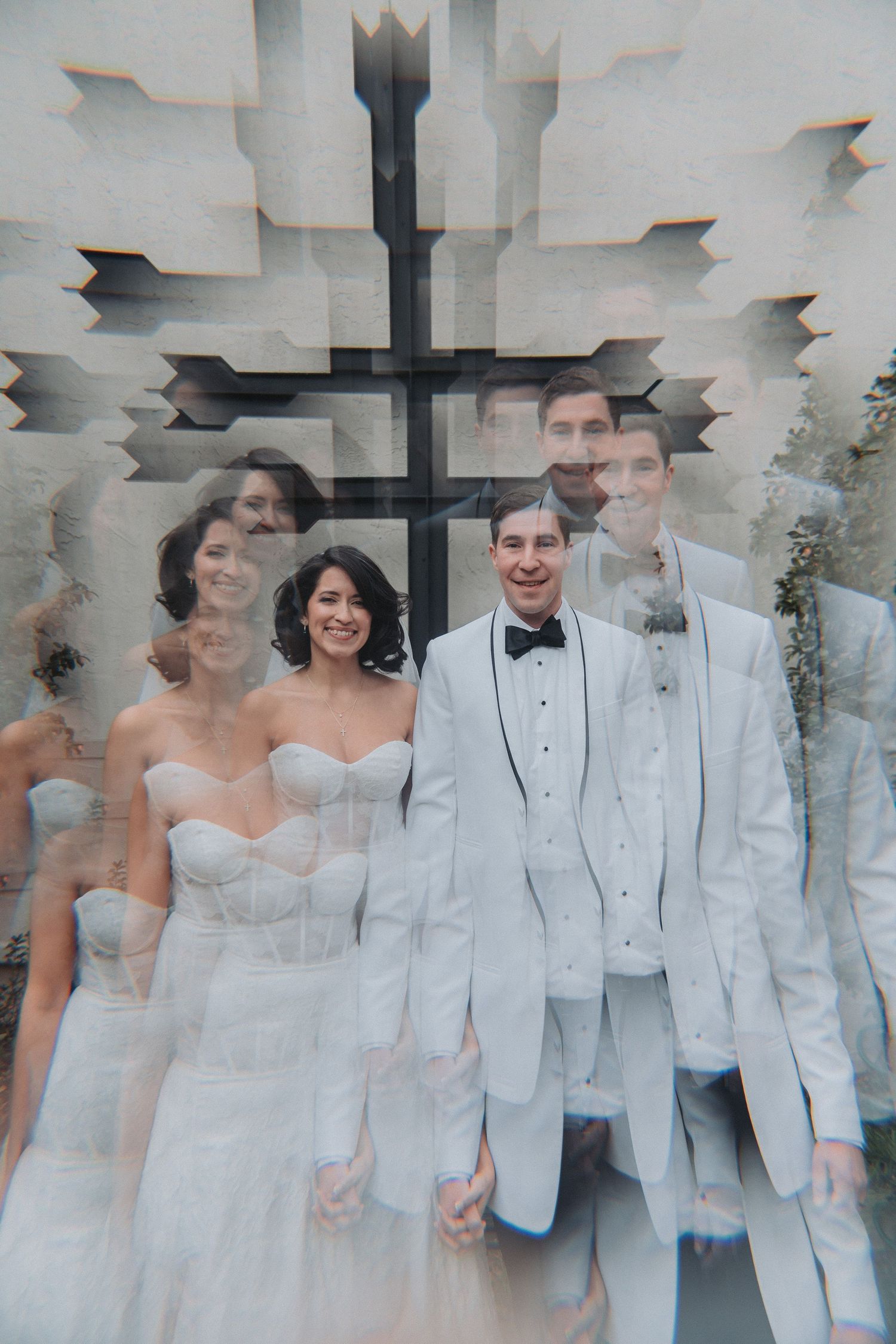 Double exposure wedding photo of bride in white gown and groom in white tuxedo with cross backdrop.