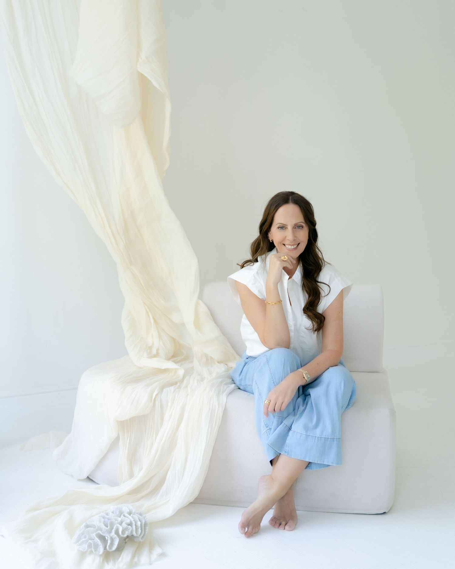 Person sitting on white couch in minimalist white room setting.