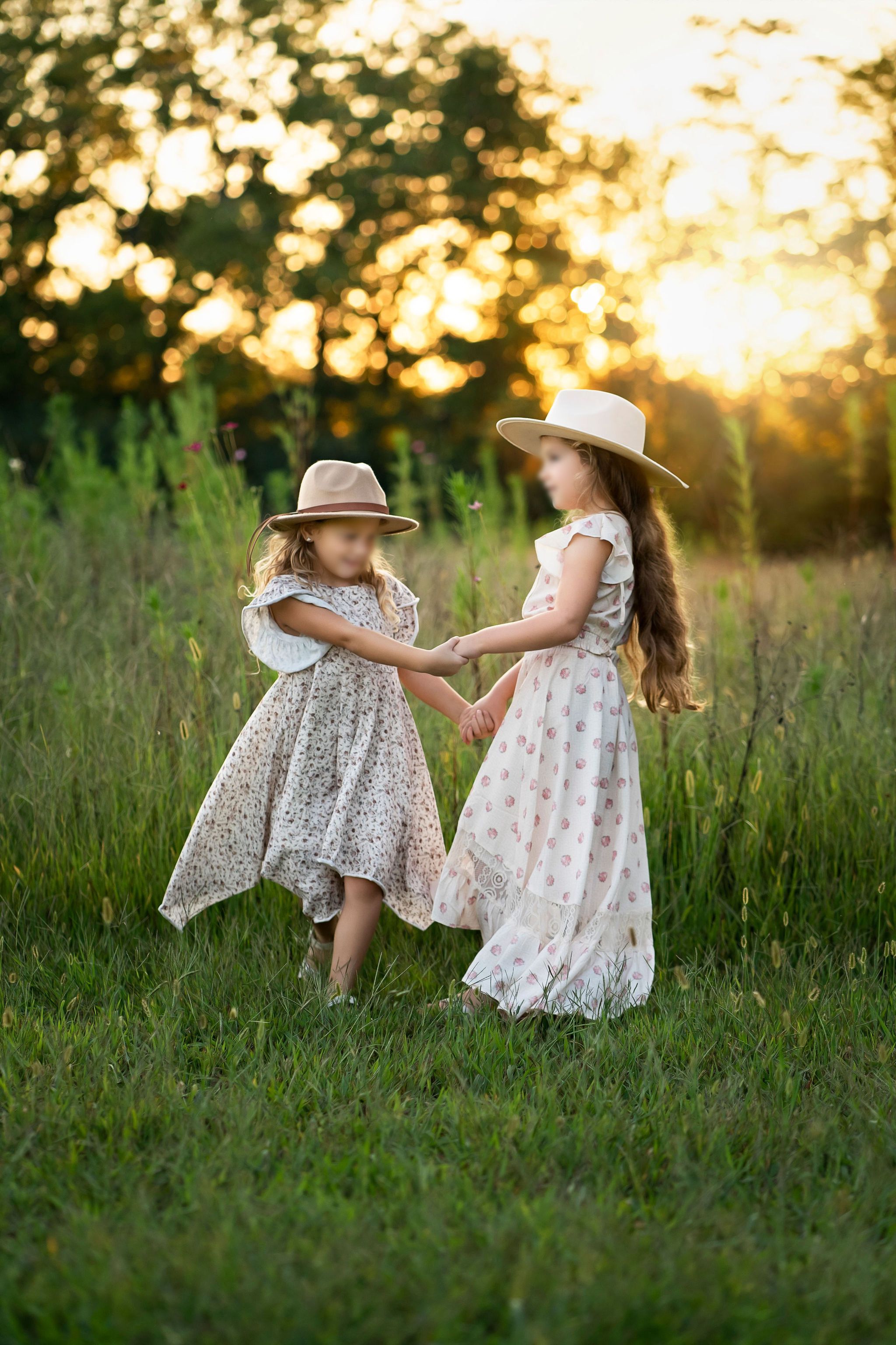 Two girls in flowing floral dresses and neutral hats during a Franklin, TN golden-hour session.