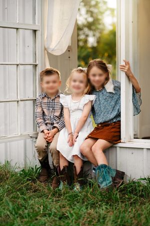 Children wearing coordinated rust, blue, cream, and tan outfits during a fall portrait session.