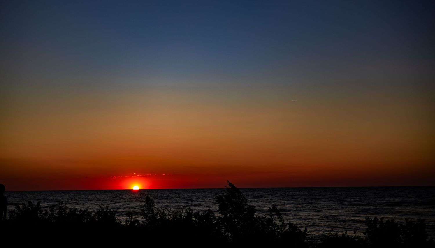 Stunning vibrant red and orange sunset over the ocean horizon at dusk.
