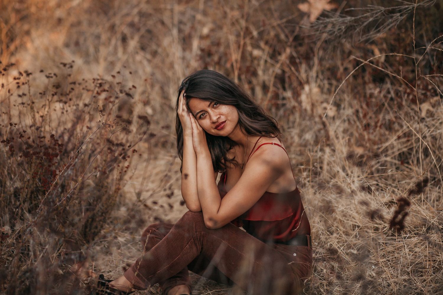 A woman sitting in a golden brown field with a calm expression on her face.