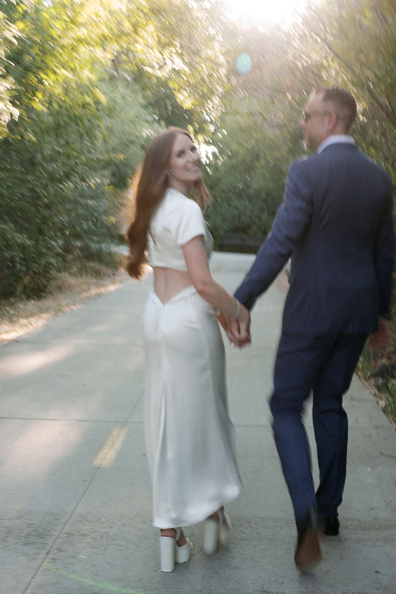 blurry image of a bride and groom walking a park path at the greenbelt in boise