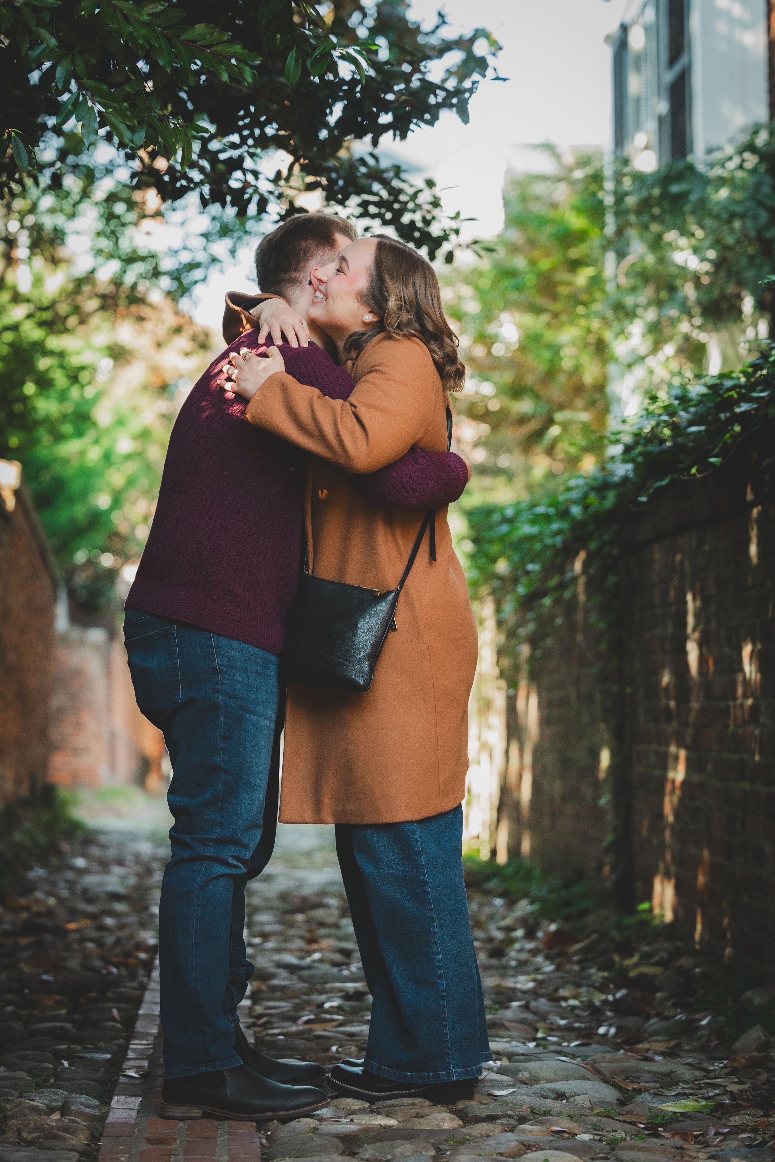 Couple embracing with full joy in a historic cobblestone alleyway moments after their surprise proposal