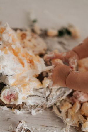 Baby hands smashing into a decorated cake during a first birthday cake smash.