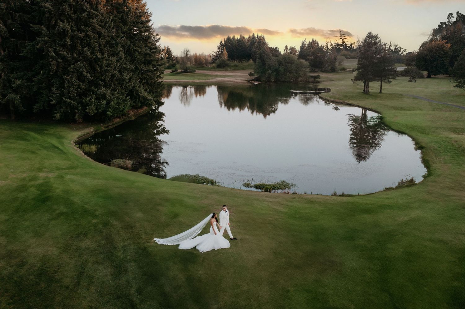 Husband and wife walking near pond on golf course in Olympia, Washington in their wedding attire.