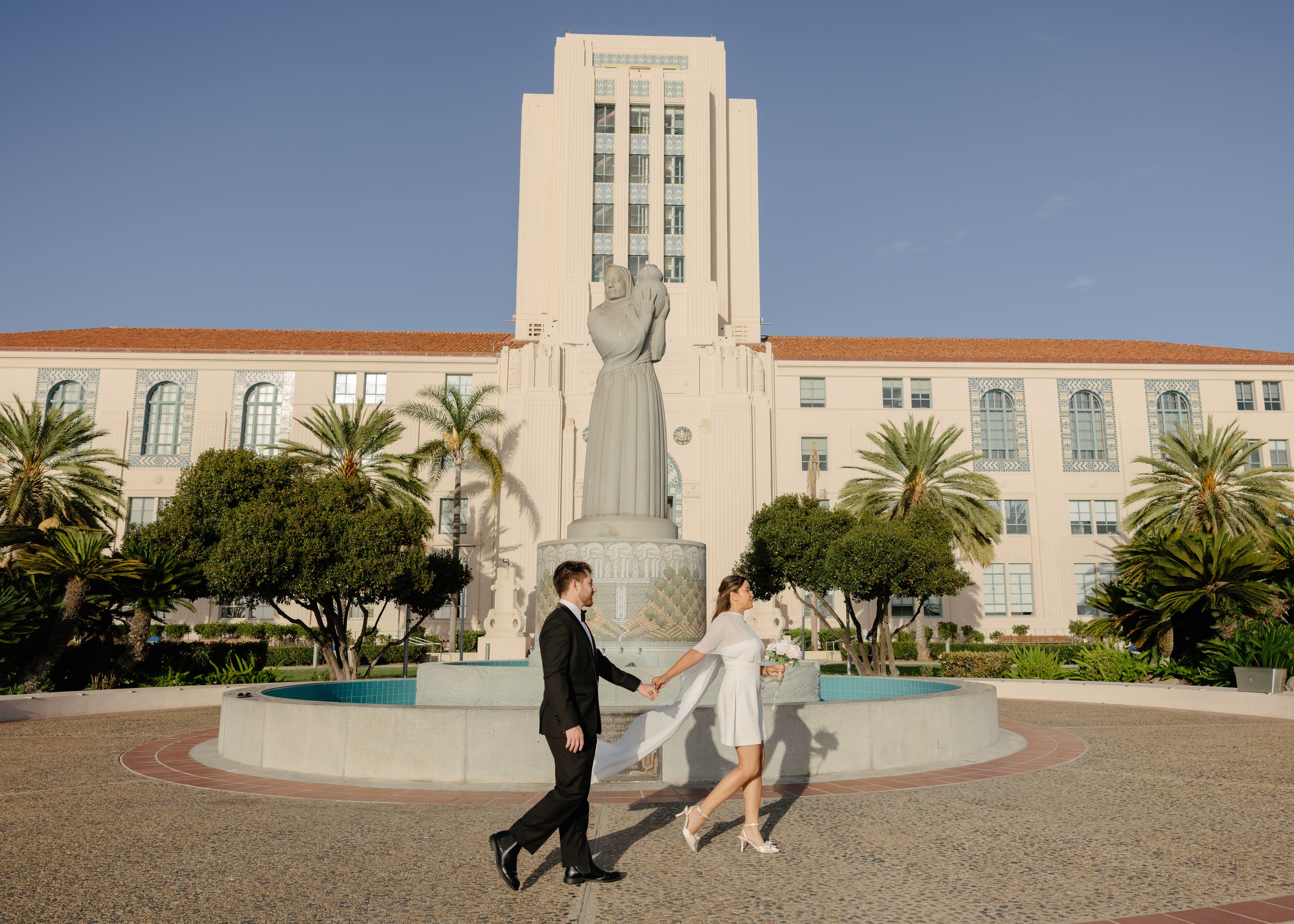 Couple dancing in front of a large statue and fountain at San Diego County Administration Center.