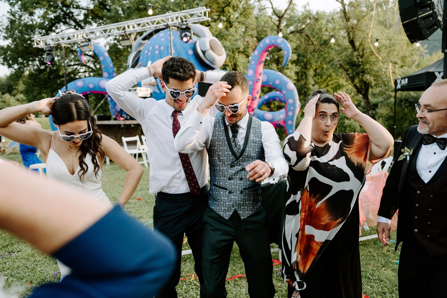 Wedding guests dance and celebrate outdoors at a colorful reception with decorations and festive attire.