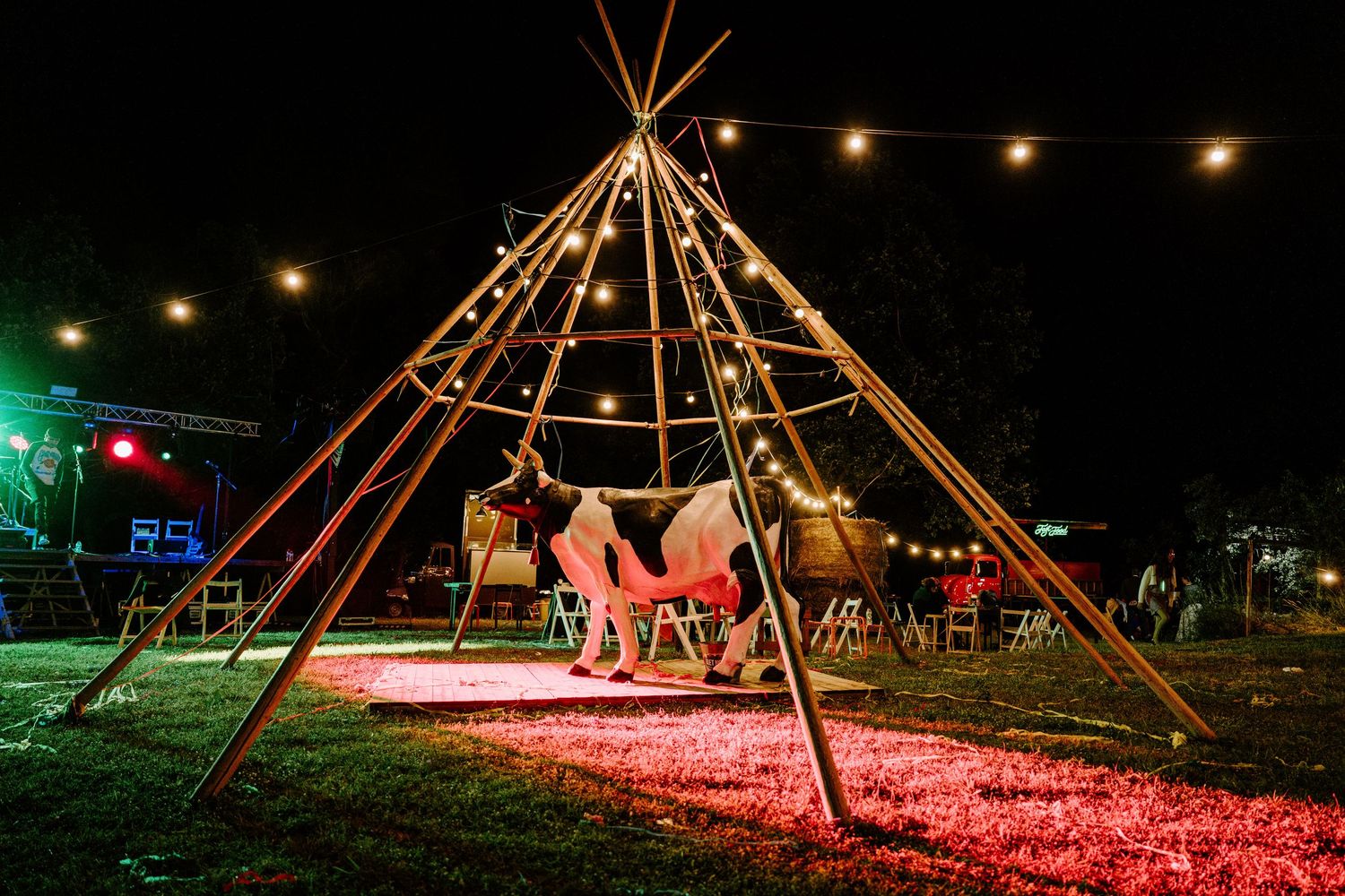 Romantic tipi structure glowing with string lights at outdoor night wedding.