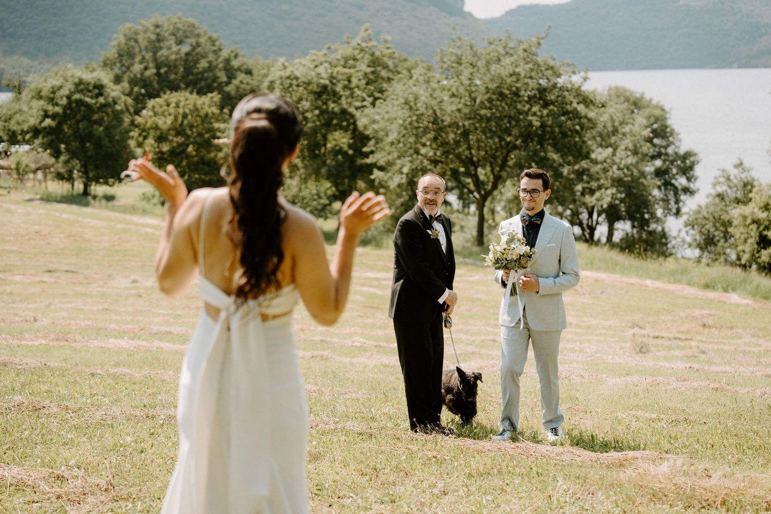 Groom sees bride for the first time during an outdoor lakeside wedding first look moment.
