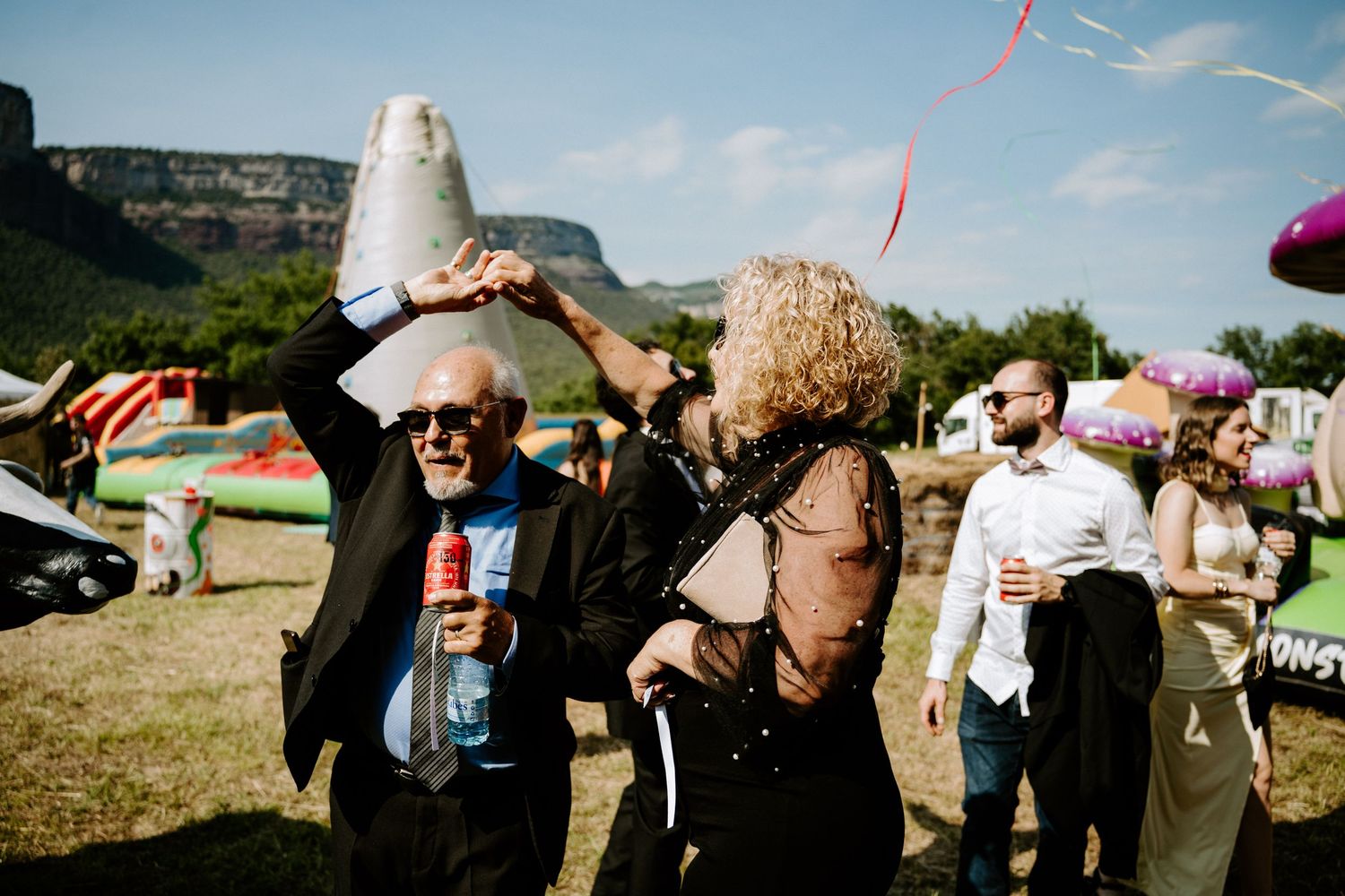 Elderly couple dancing joyfully at an outdoor wedding reception with mountain views.