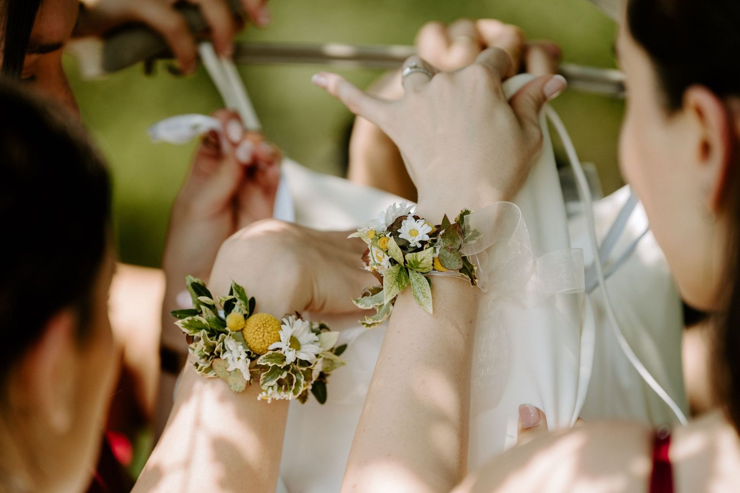 Close-up of floral wrist corsages with daisies and yellow flowers worn by wedding party members.