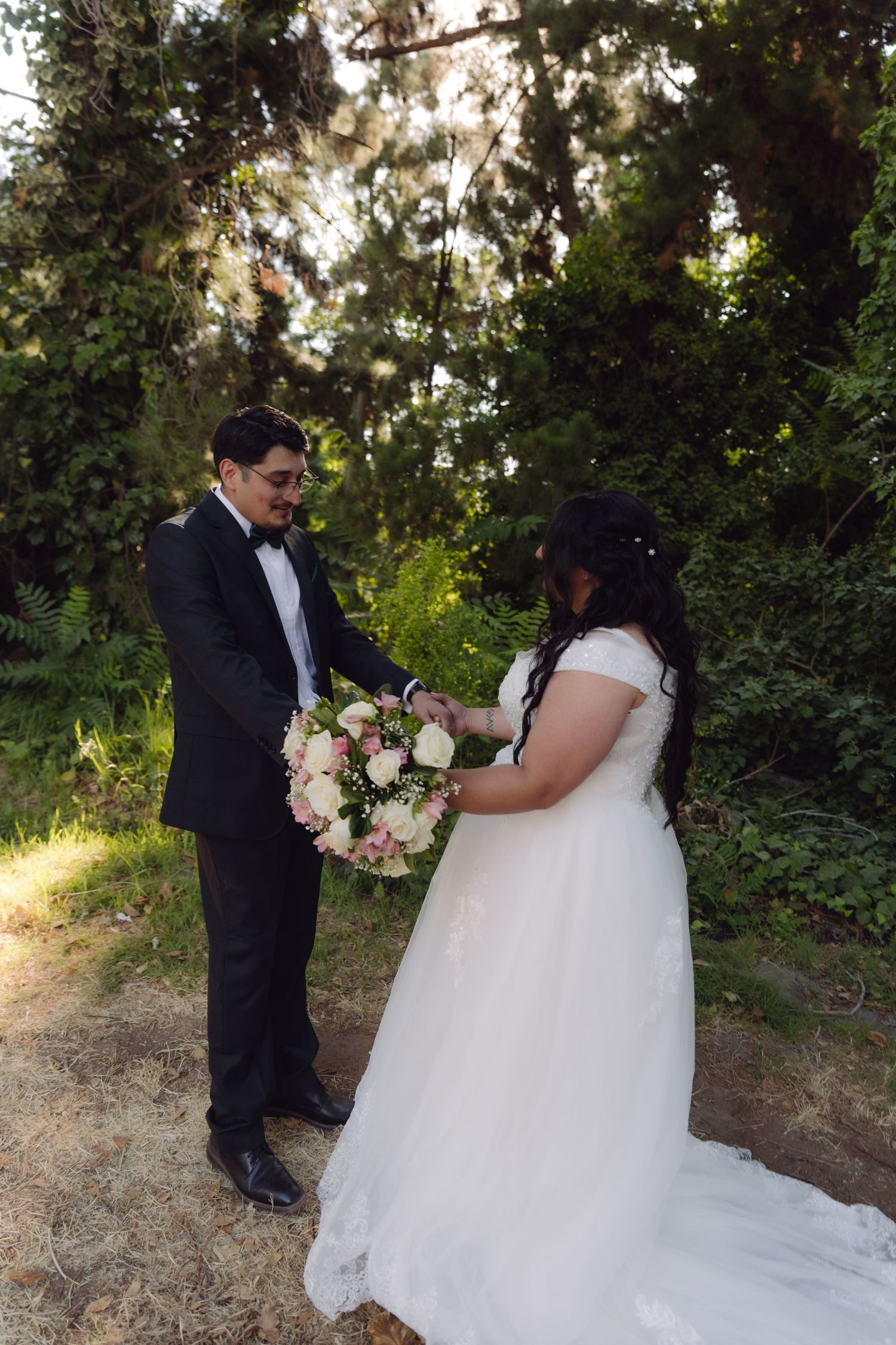 Bride and groom exchanging bouquet in a scenic outdoor garden during their wedding photoshoot.