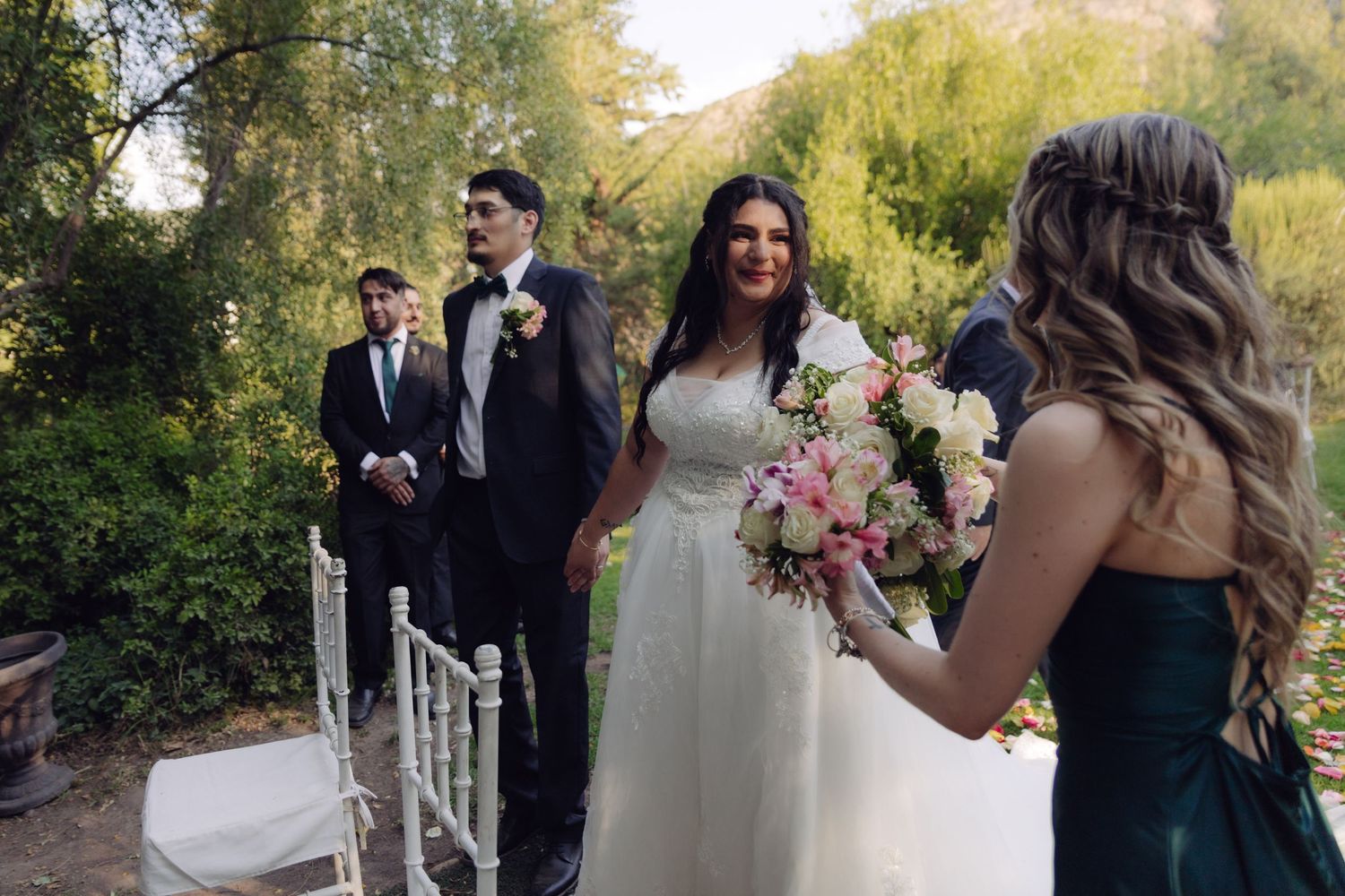 Smiling bride in white gown meets groom at outdoor wedding ceremony altar.