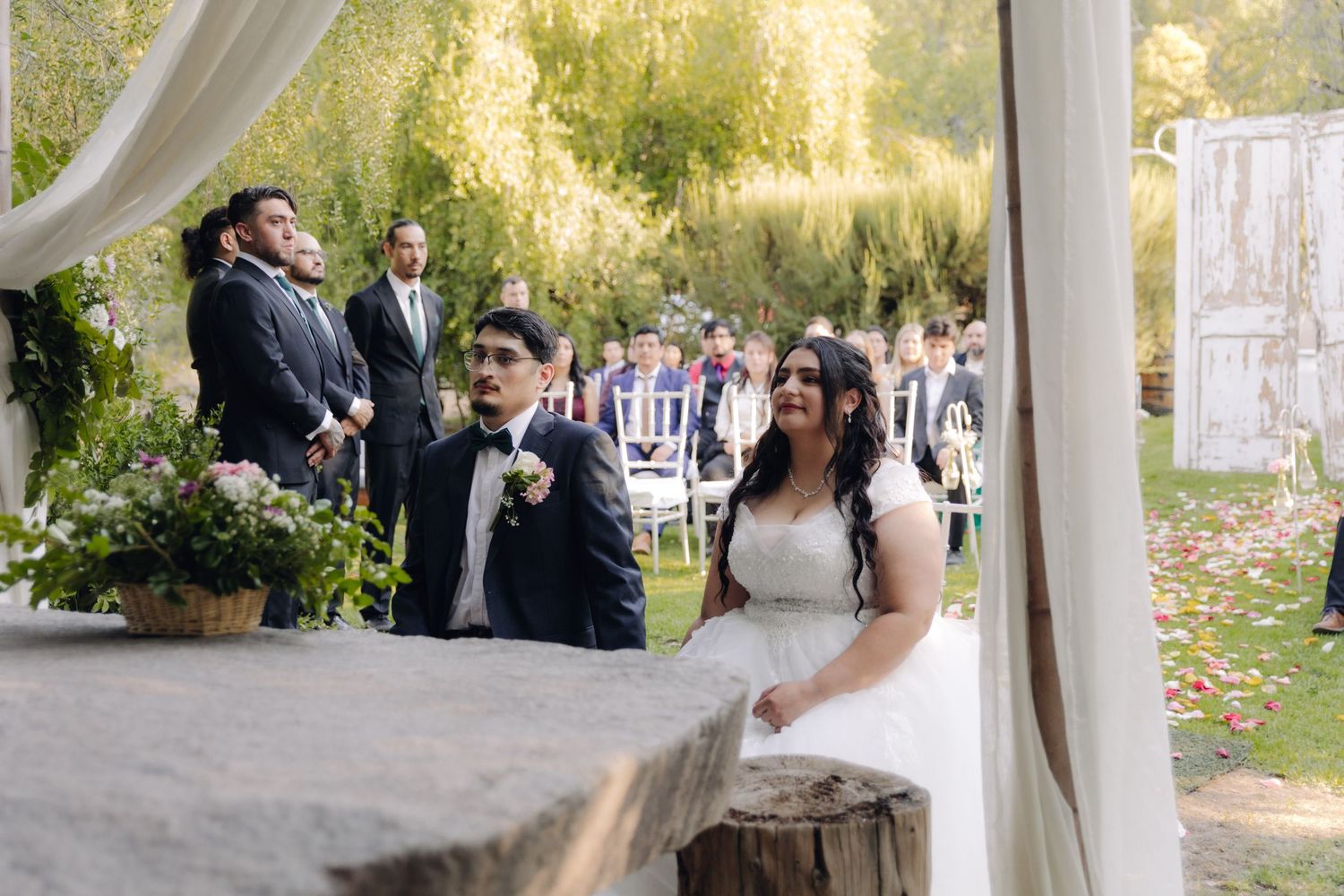 Bride and groom sharing a moment at outdoor garden wedding ceremony with guests seated.