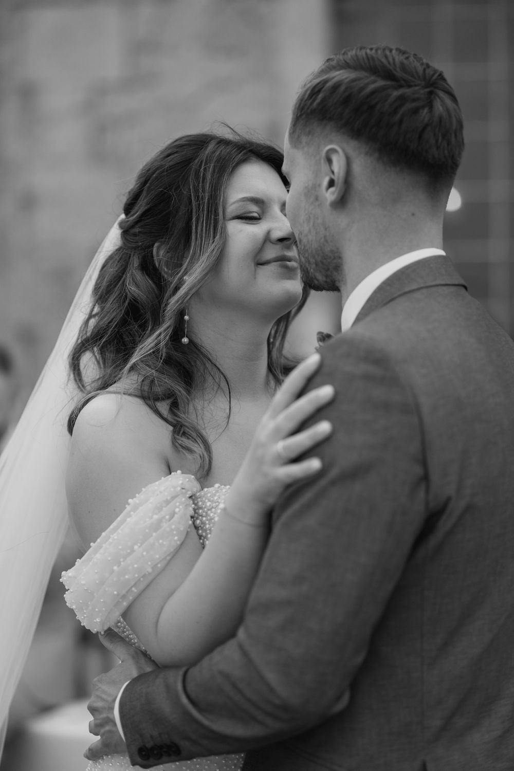 Black and white photo of bride smiling at groom during an intimate wedding moment.