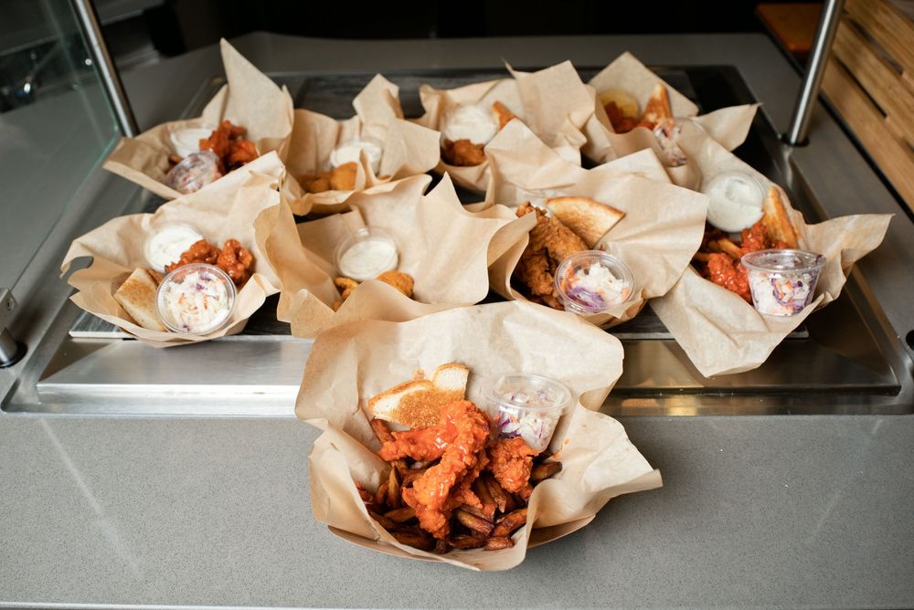 Crispy fried chicken wings served in paper-lined baskets arranged on a metal tray at a restaurant.
