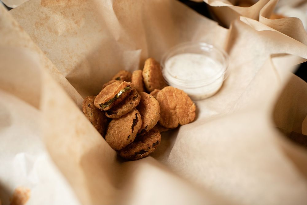 Crispy fried cookies served in parchment-lined basket with a small cup of white dipping sauce.