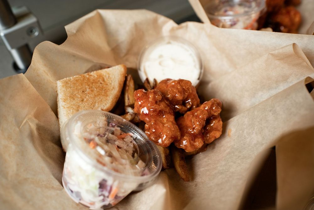 Crispy buffalo chicken wings served in a paper-lined basket with ranch dipping sauce and toasted bread.