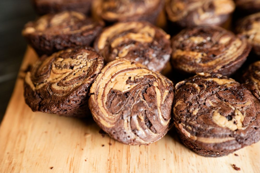 Swirled chocolate and peanut butter marble muffins displayed on a wooden cutting board.