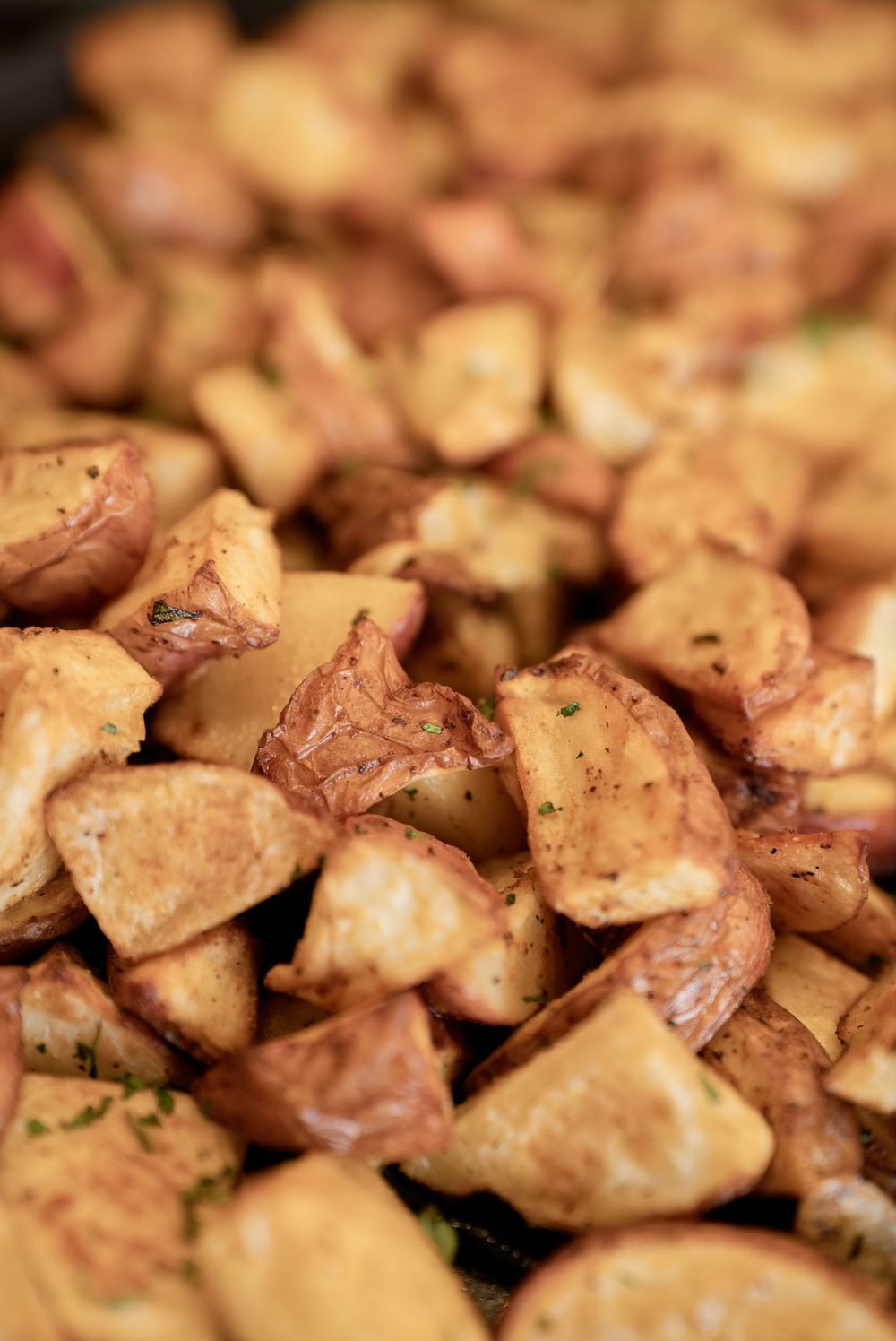Crispy roasted red potato chunks seasoned with herbs, golden brown and perfectly cooked on a baking sheet.