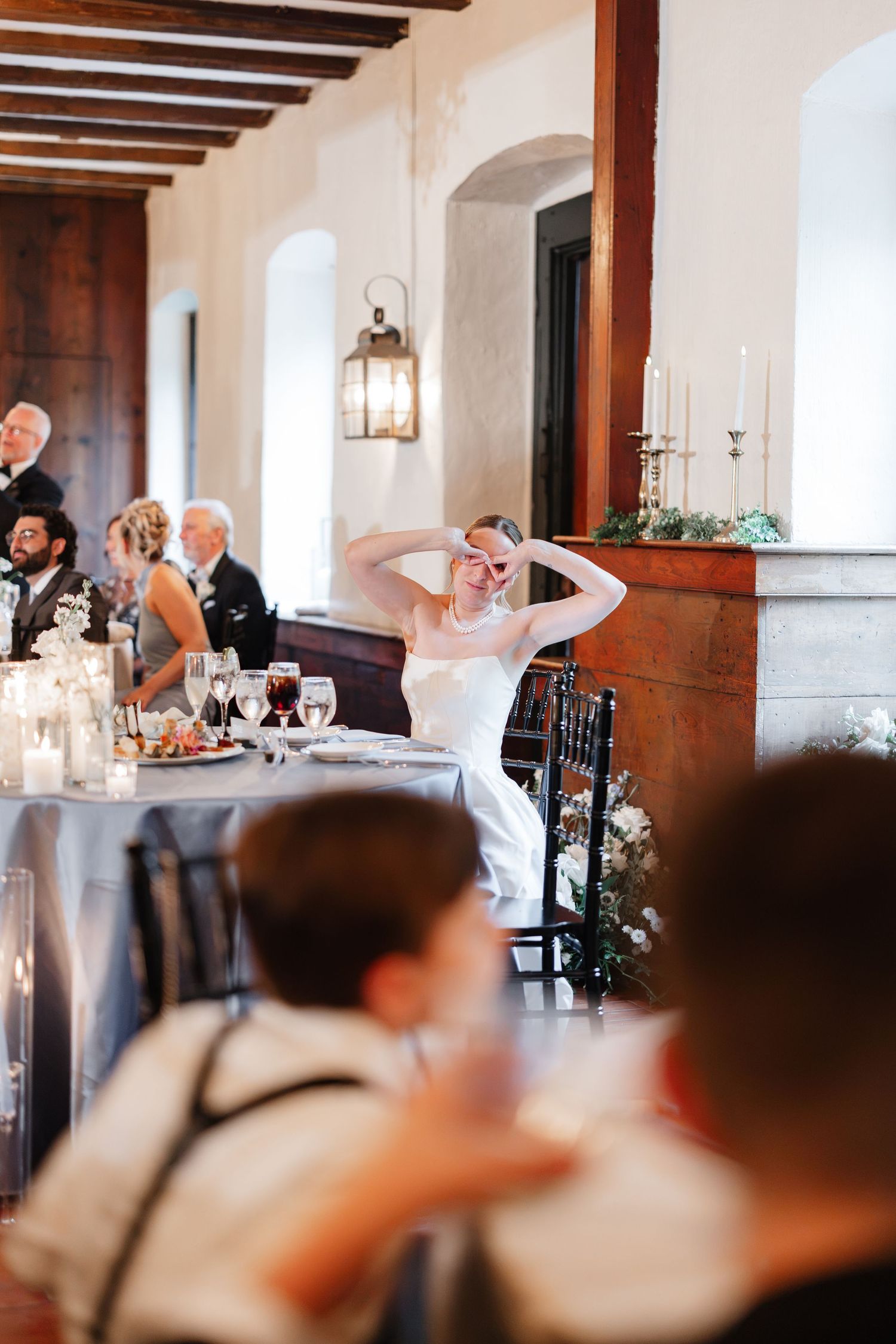 Bride laughs joyfully at the sweetheart table during her wedding reception dinner.