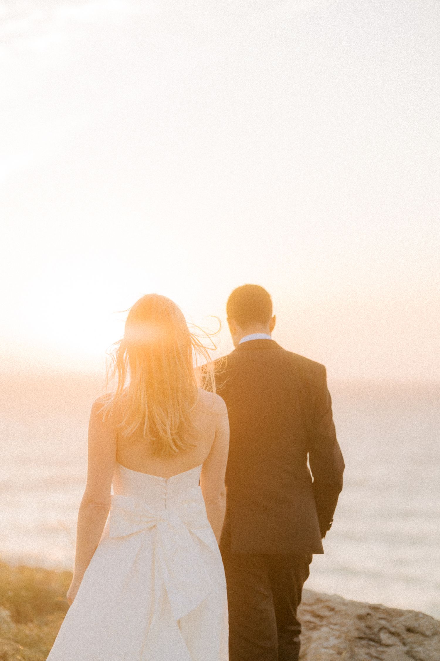 Bride and groom walking towards the Atlantic Ocean during golden hour after their destination wedding in Cascais, Portugal.