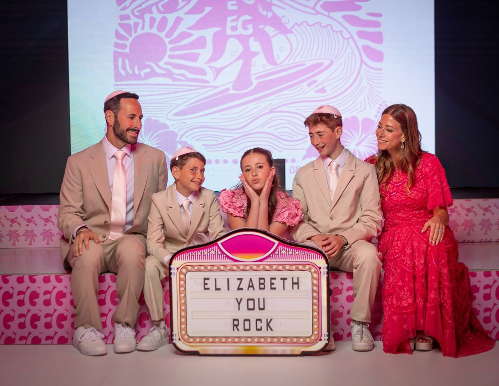 Family of five poses with a pink marquee sign reading Elizabeth You Rock at a festive pink-themed celebration.