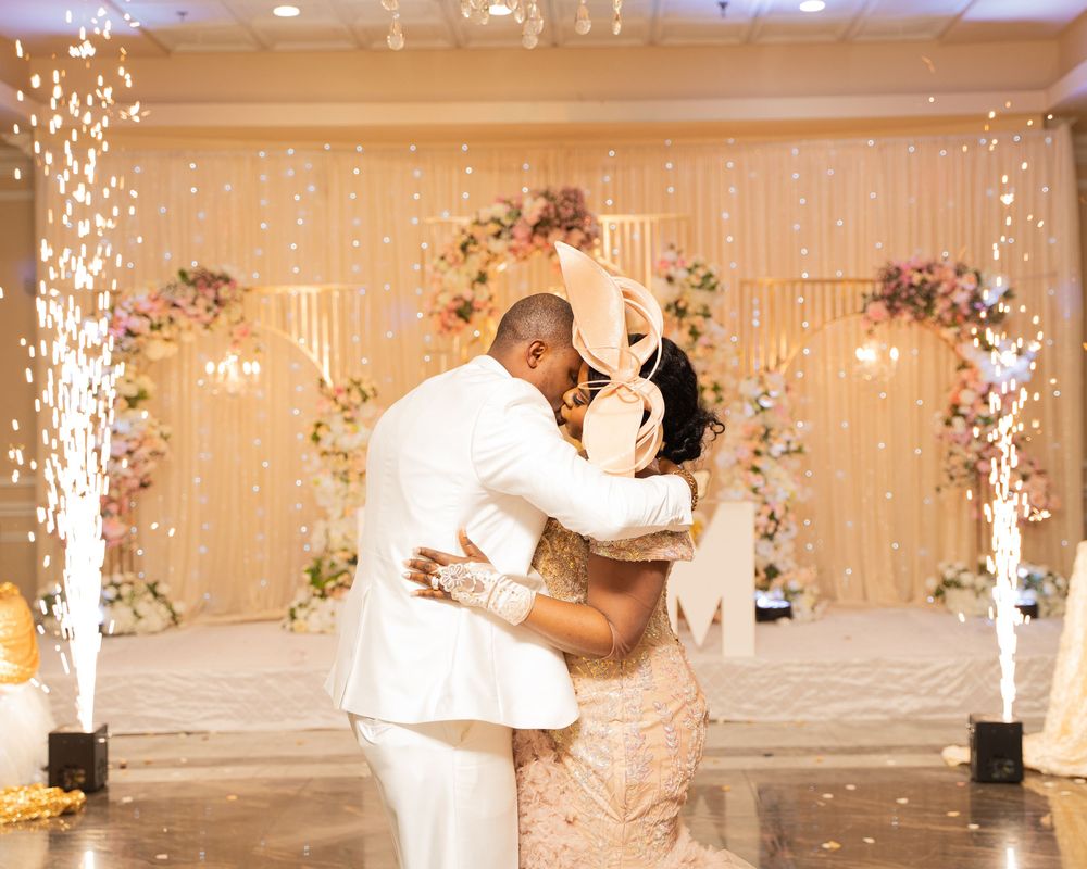 Couple shares first dance at elegant wedding reception with floral arch, fairy lights, and sparkling cold sparklers.