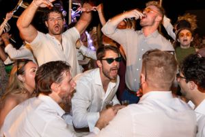 Group of people in white shirts celebrating at a lively wedding reception party.
