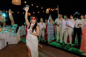 Woman in white dress dancing at outdoor evening party with string lights and guests in background.