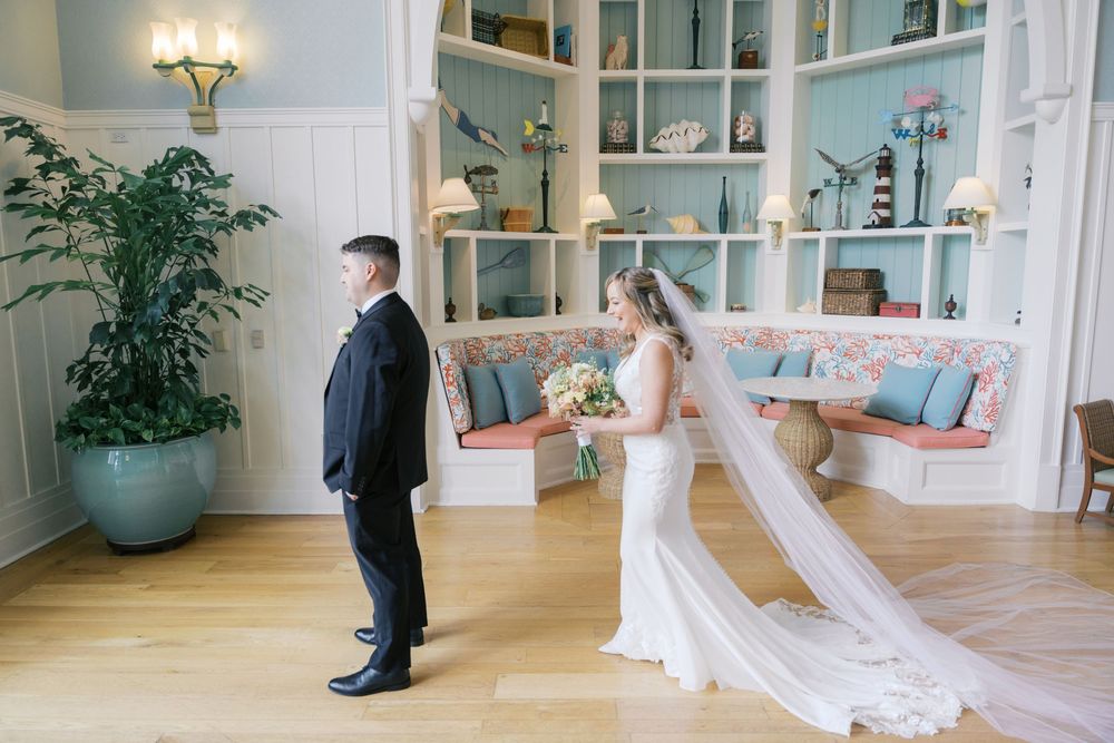 Bride and groom share a first look moment in an elegant room with teal shelving and hardwood floors.
