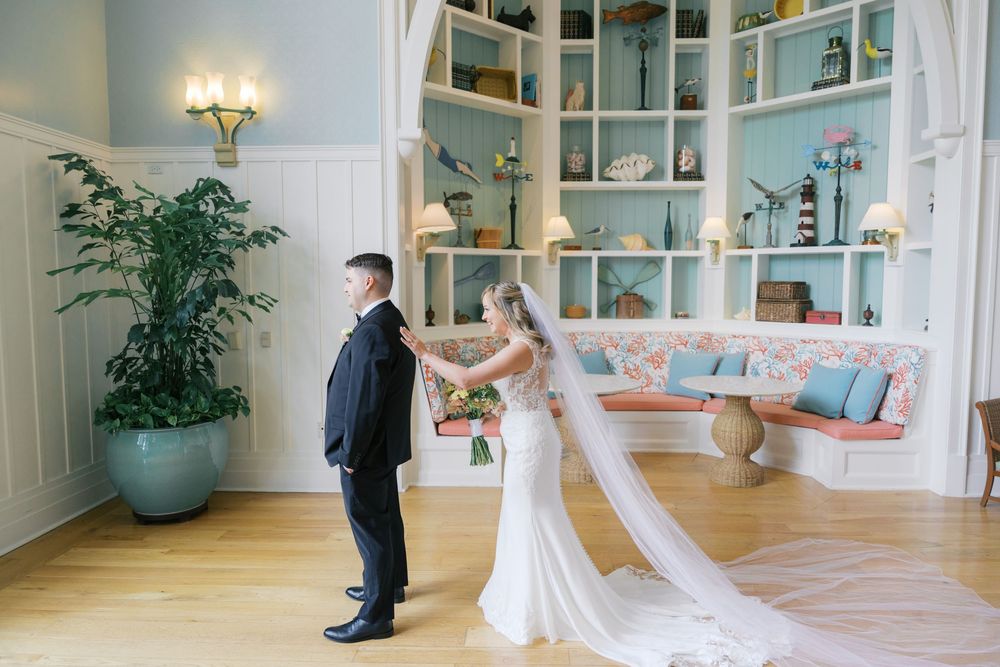 Bride surprises groom with a first look moment inside a nautical-themed hotel room with blue shelving.