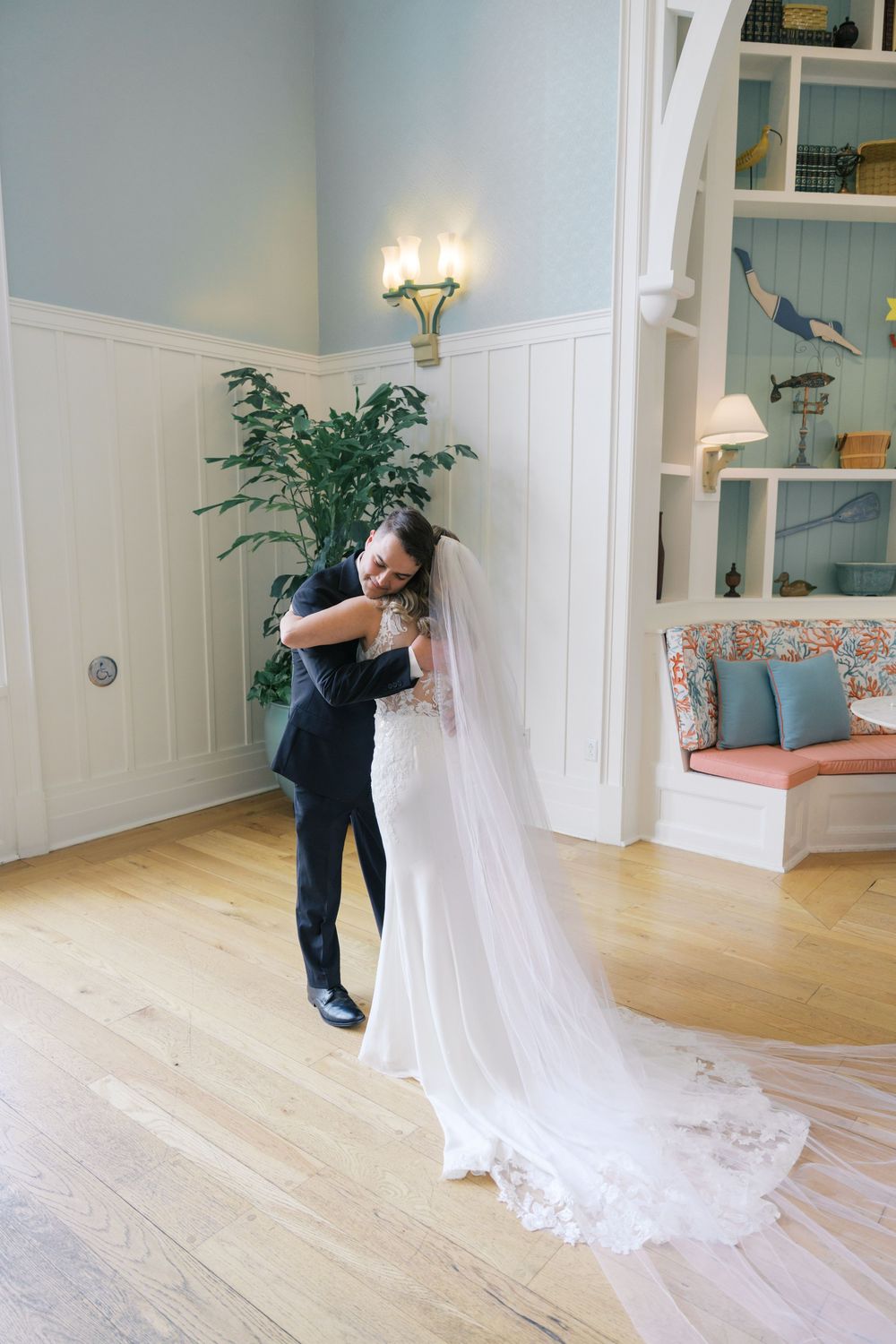 Bride and groom share a tender embrace during first dance in an elegant blue and white interior.