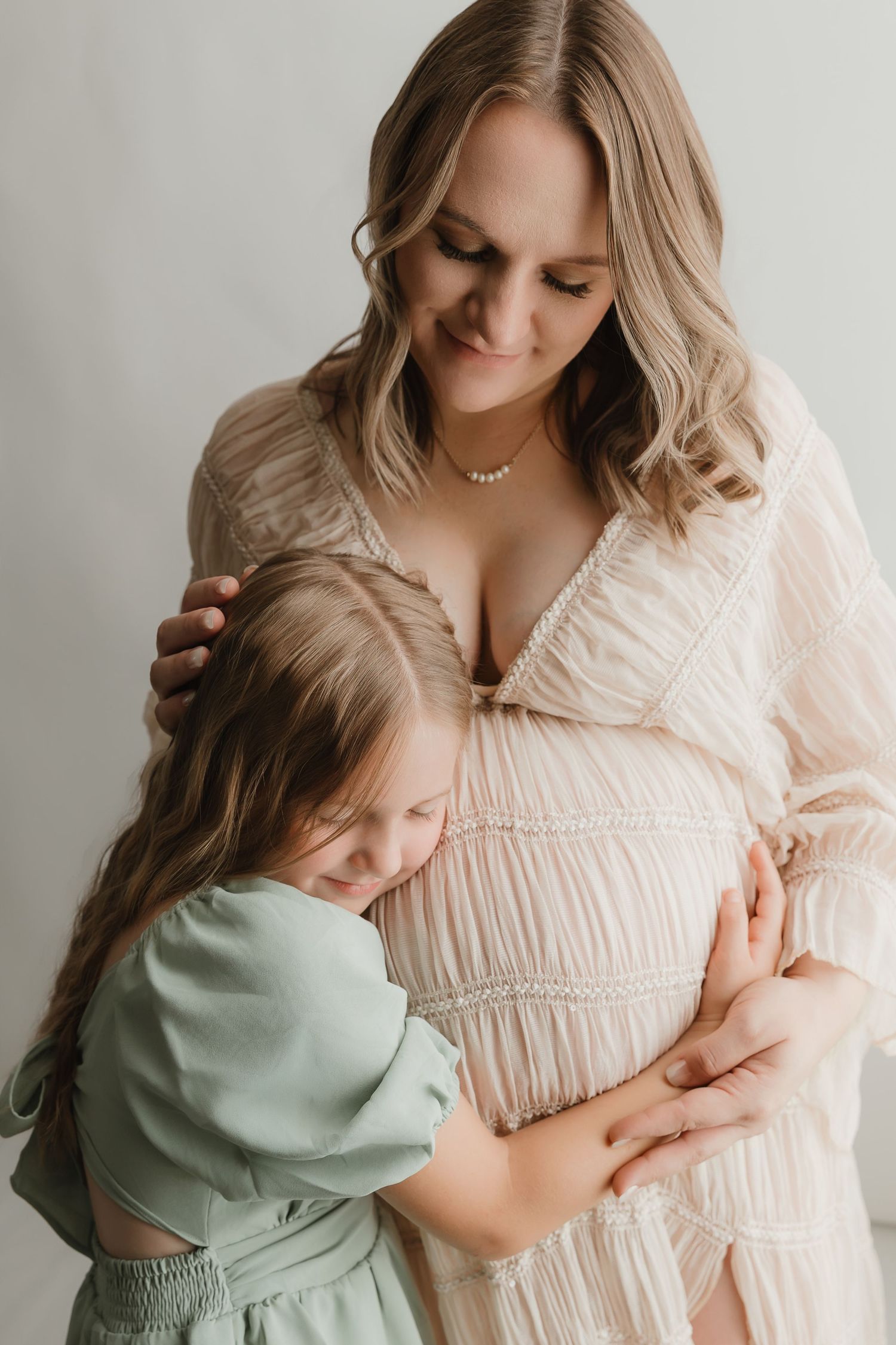 Expecting Mother with daughter hugging her baby bump during a motherhood portrait session in East Texas