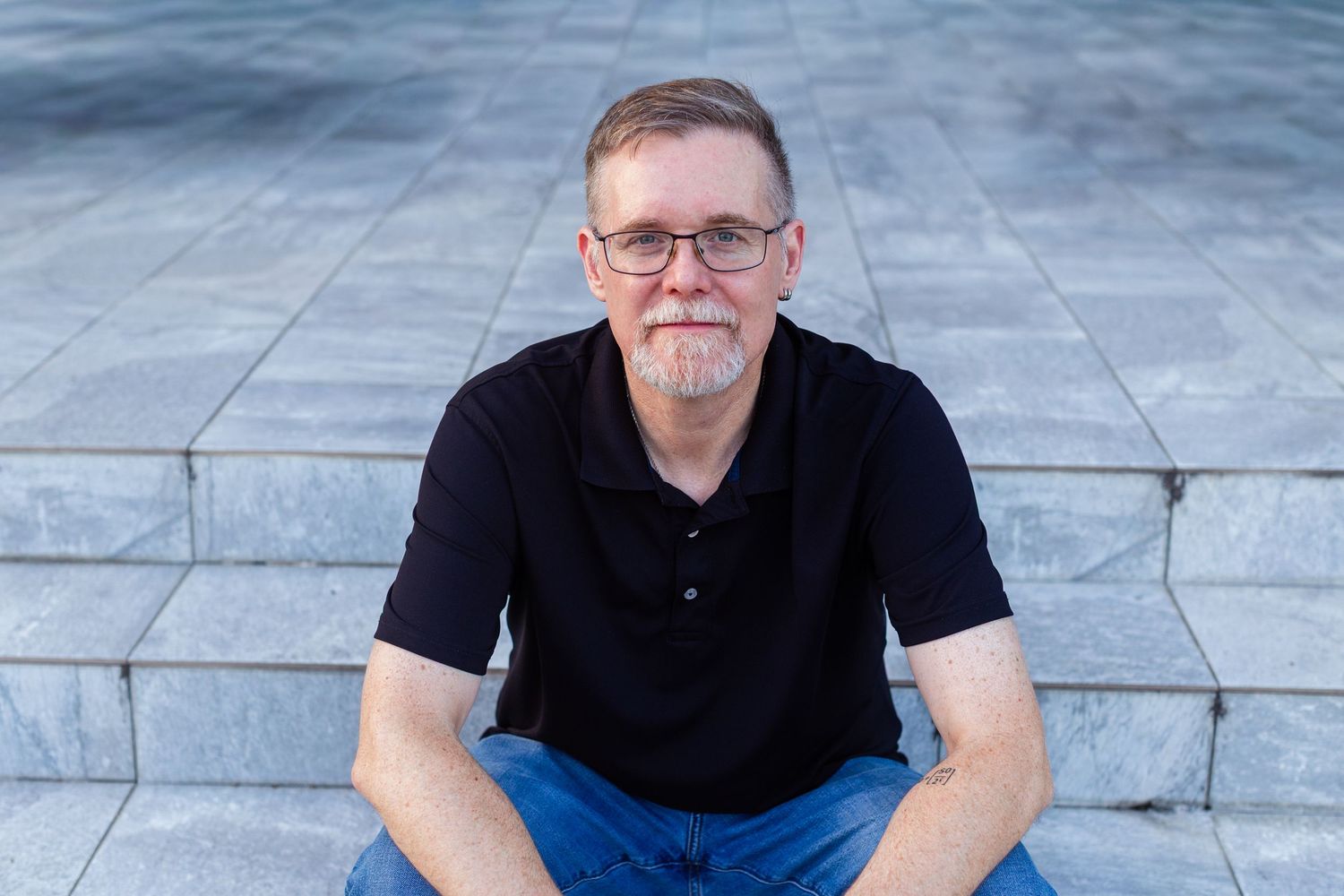 Headshot of a man sitting on gray tiled steps. Guaynabo, Puerto Rico.