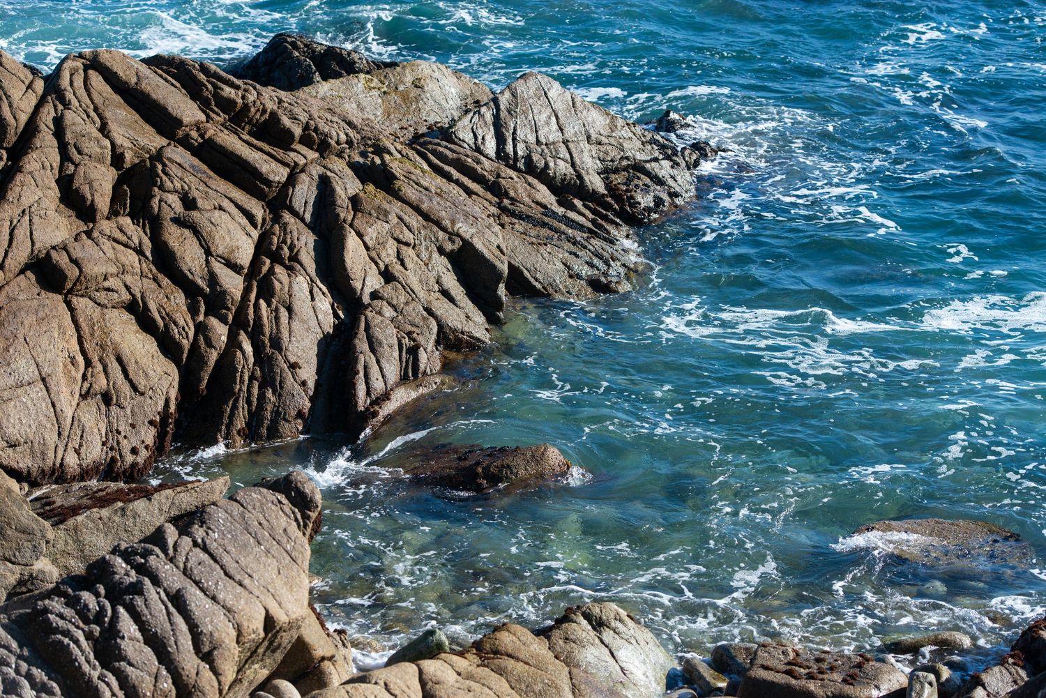 Rocky coastal cliffs meet crashing blue ocean waves in a stunning seaside landscape.