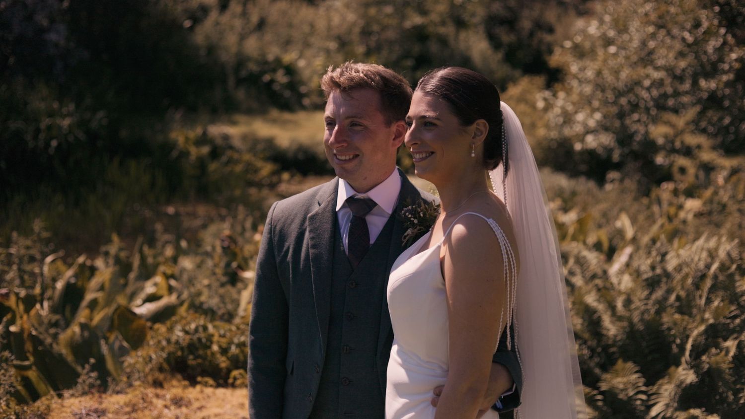 Bride and groom holding each other in golden greenery, smiling and happy at Marl House, Whithorn