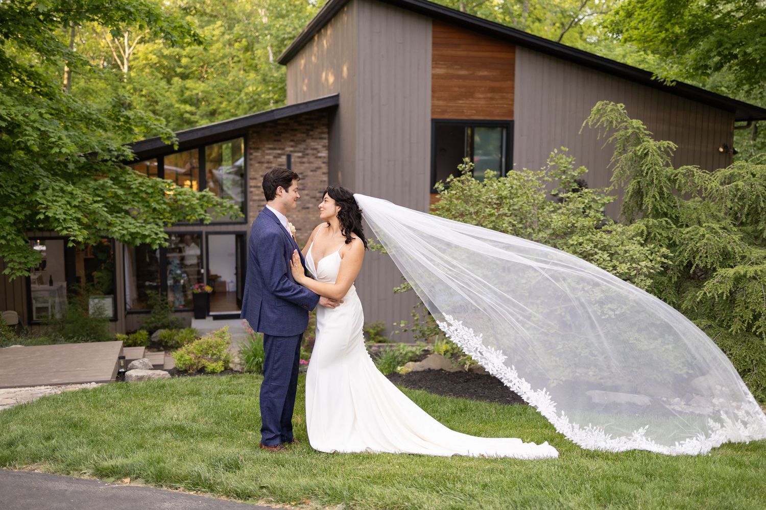 Elegant bride and groom pose beside a classic car, capturing timeless romance at an autumn wedding.