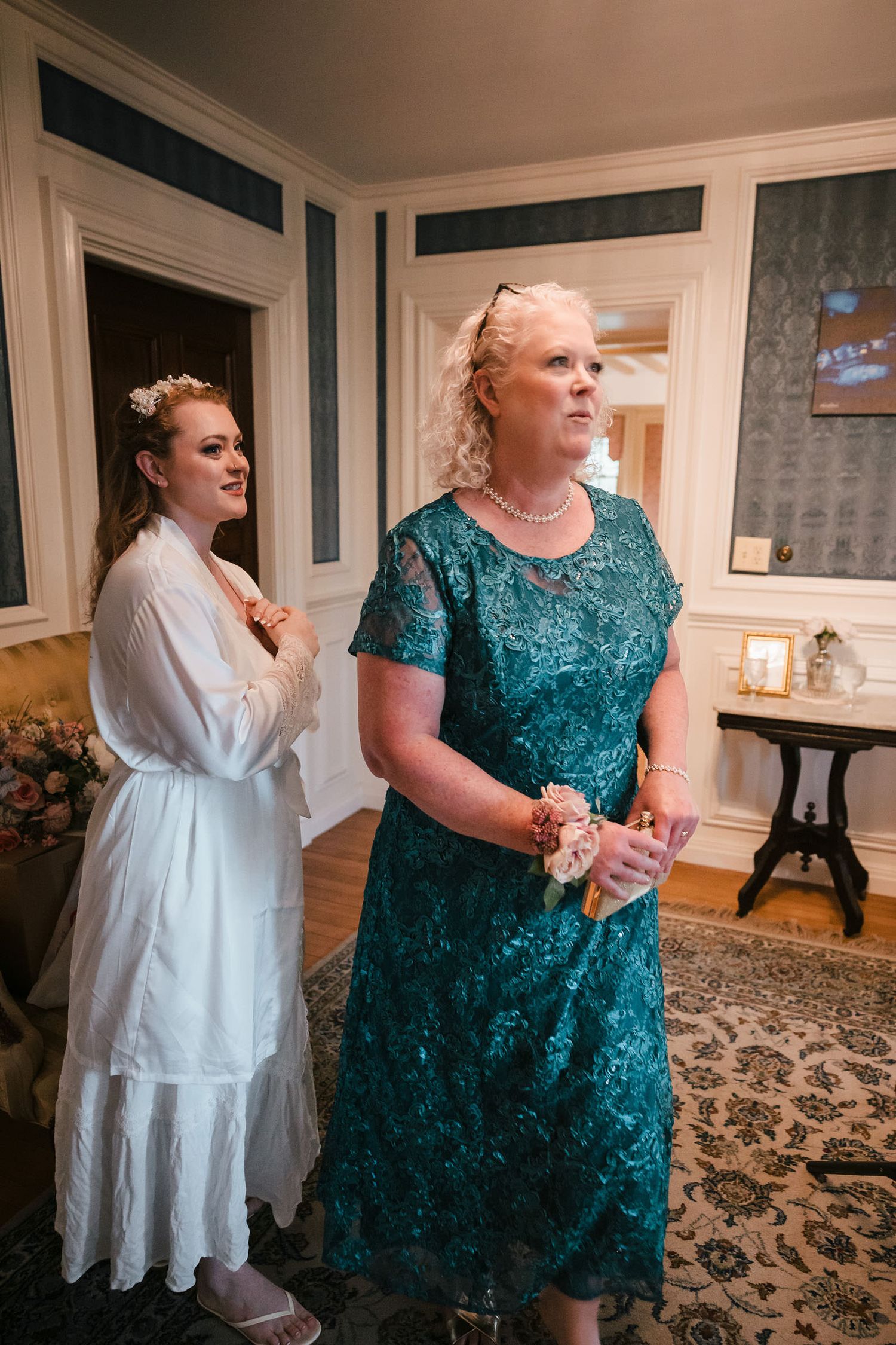 Mother looking up at her daughter's wedding dress, made from pieces of her own wedding gown, hanging at Searles Castle.