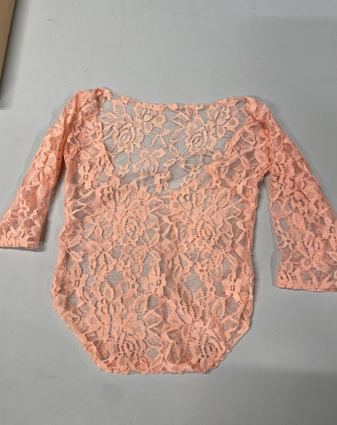 Peach floral lace long sleeve bodysuit with scoop back and sheer overlay detail.