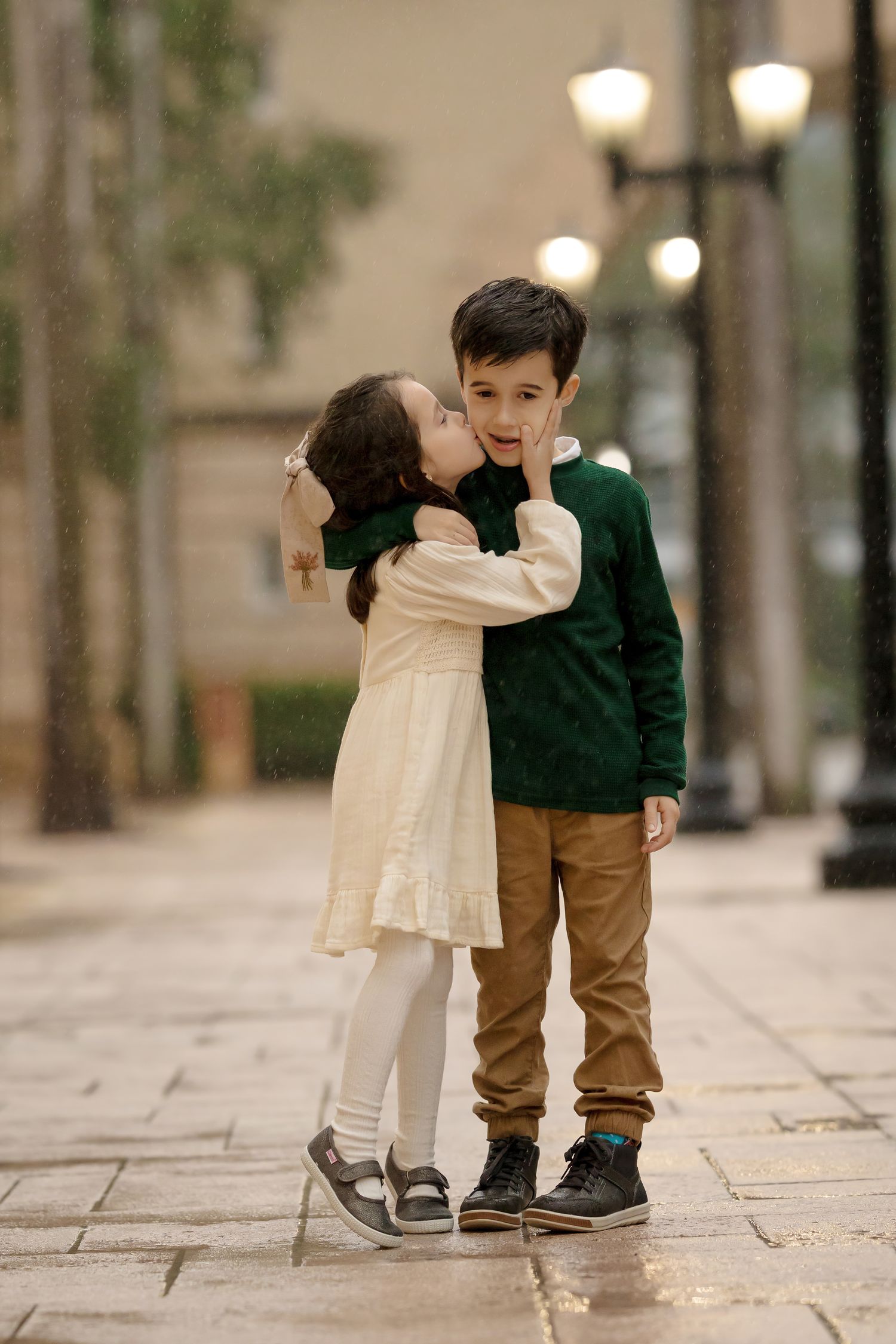 Sister kissing her brother on the cheek during an urban family session