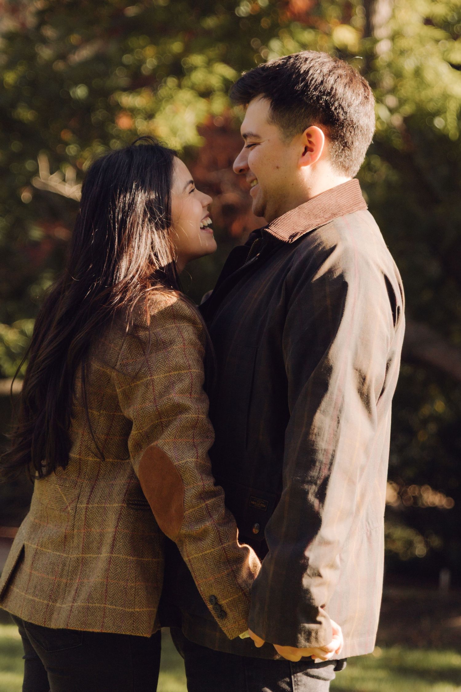 Smiling couple gazing lovingly at each other in a sunlit autumn park.